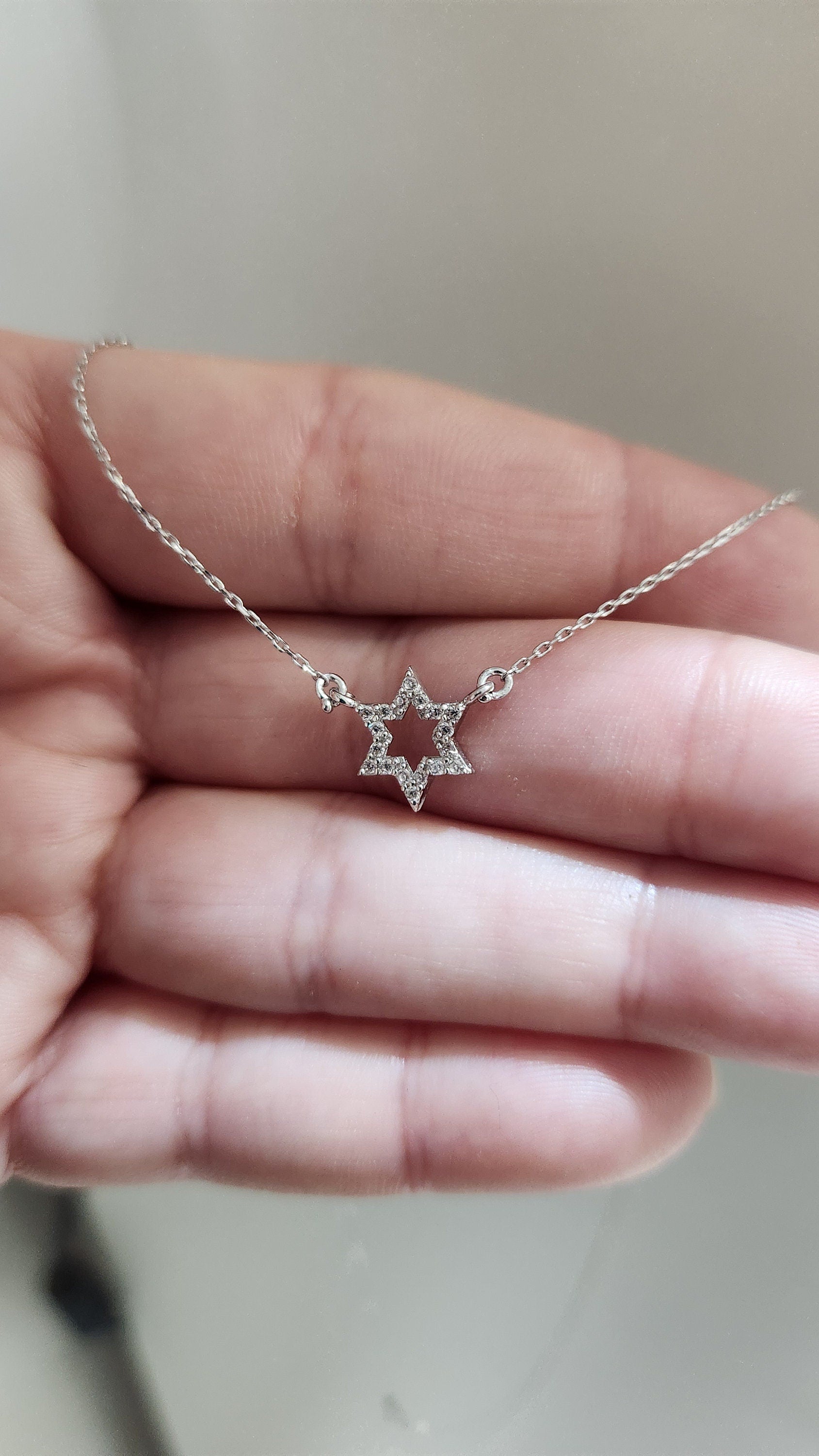 a person holding a star necklace in their hand